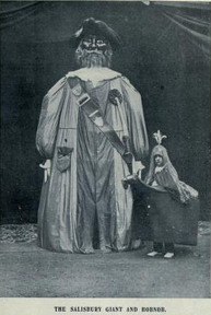 Auto-generated description: A person in a giant costume with a large head and elaborate hat stands next to a smaller figure dressed in a hobby horse outfit, labeled The Salisbury Giant and Hobnob.