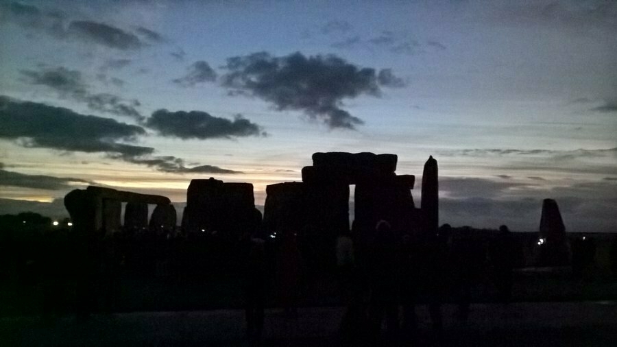 Auto-generated description: A silhouette of Stonehenge stands against a colorful dusk sky.