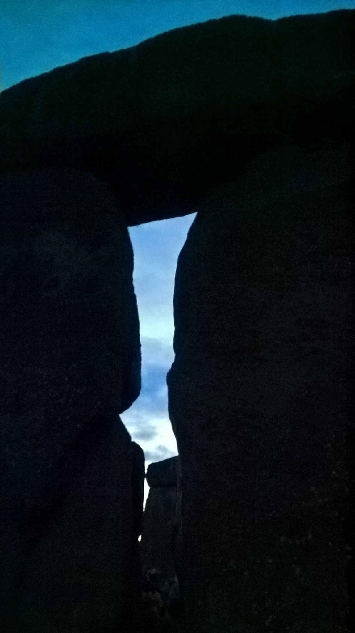 Auto-generated description: Two large stone pillars are silhouetted against a dusky sky.