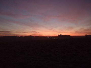 Auto-generated description: A serene landscape at dawn or dusk features a colorful sky and a silhouetted horizon.