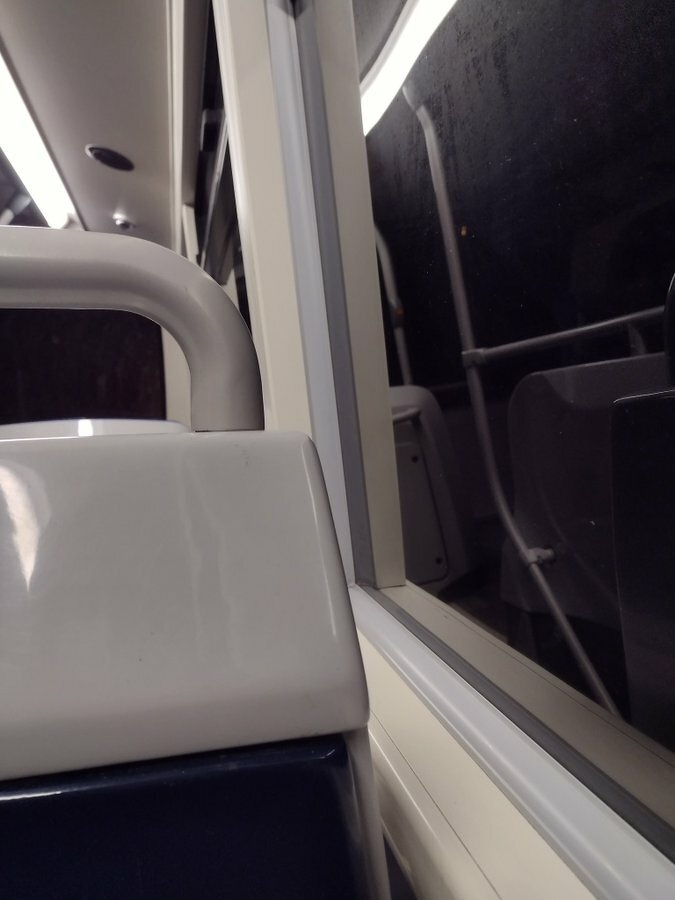Auto-generated description: A view of an empty train or bus interior showing seats and a window reflecting the inside.